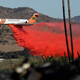A plane drops fire retardant on a wildfire Friday, Dec. 8, 2017, in Fallbrook, Calif. Image: AP Photo/Gregory Bull